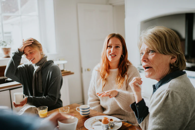 3 women at a kitchen table looking taken aback