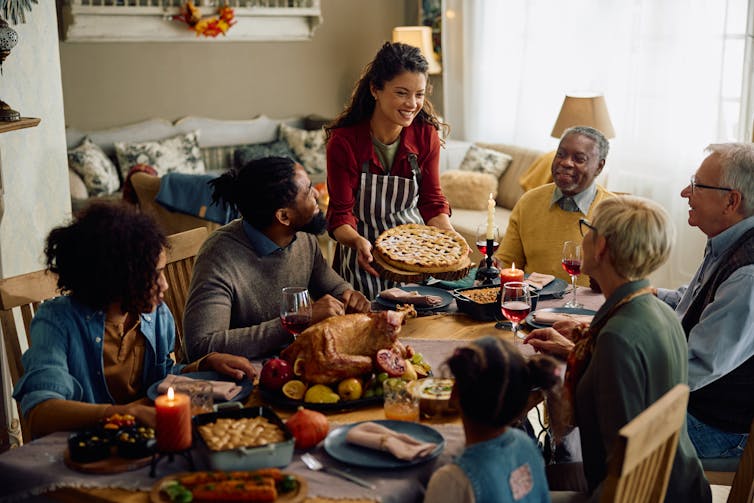 woman bringing pie to a family dinner table