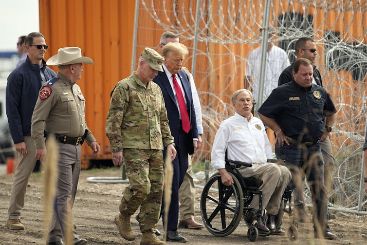 Several men walk with another man in a wheelchair.