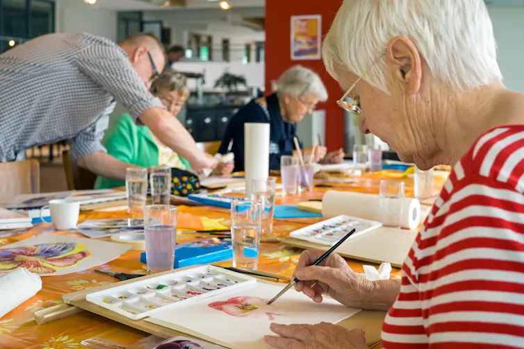 An older woman paints.