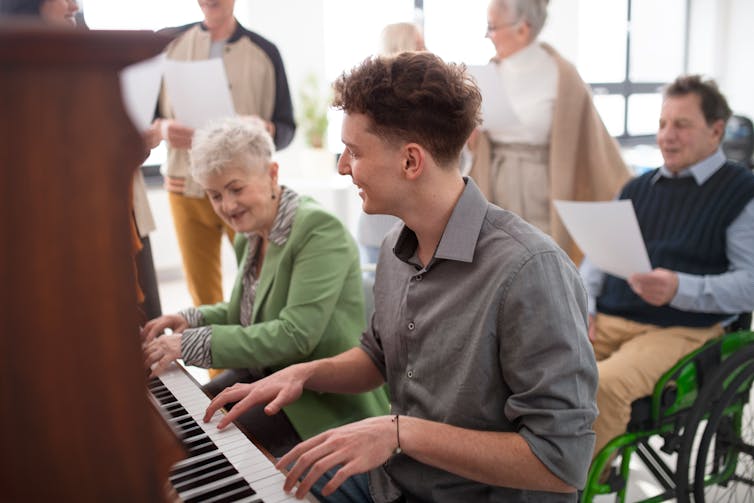 An older woman and a younger man at a piano.
