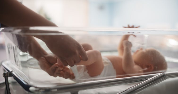 A baby in a hospital crib.