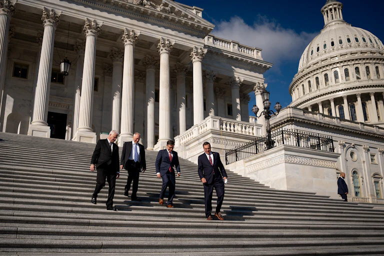 Four men in suits descend the U.S. Capitol's steps.