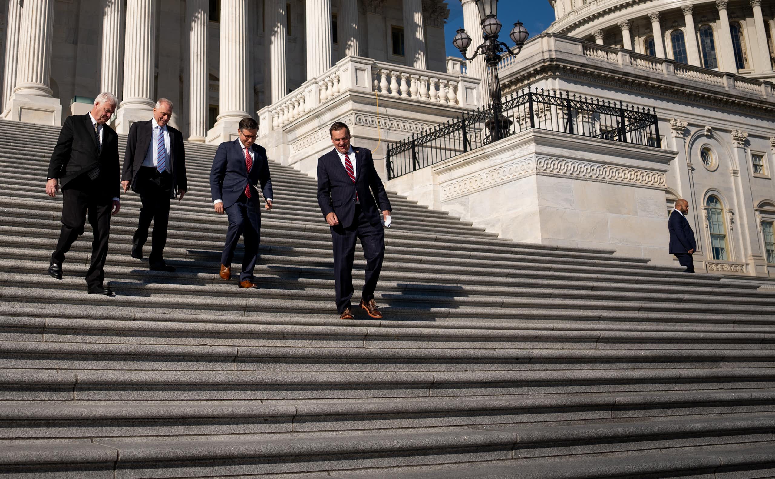 Four men in suits descend the U.S. Capitol's steps.