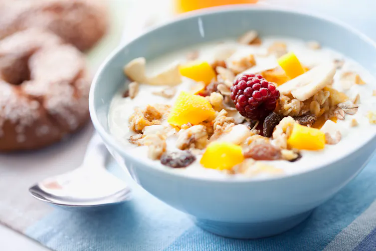 A bowl of cereal with fresh fruit on top.