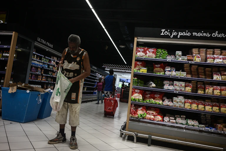 Un homme dans les rayons d'un supermarché regarde au fond de son sac.