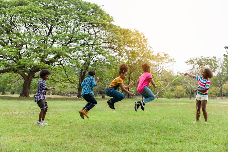A group of children playing jump rope in a park
