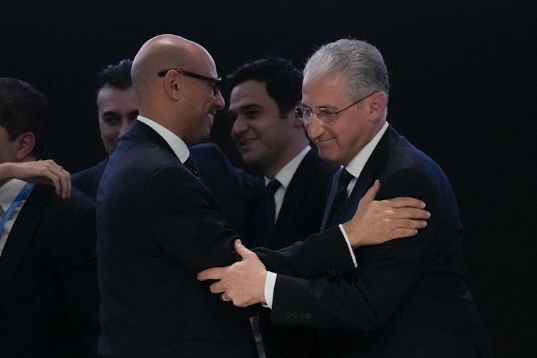 two happy men in dark suits embrace