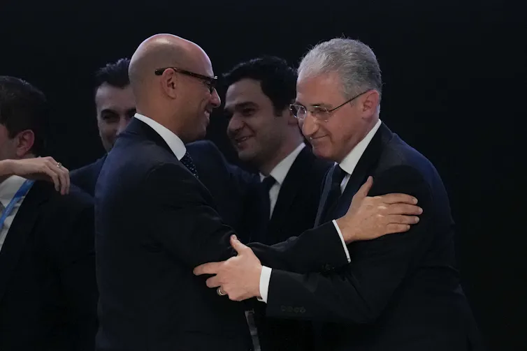 two happy men in dark suits embrace