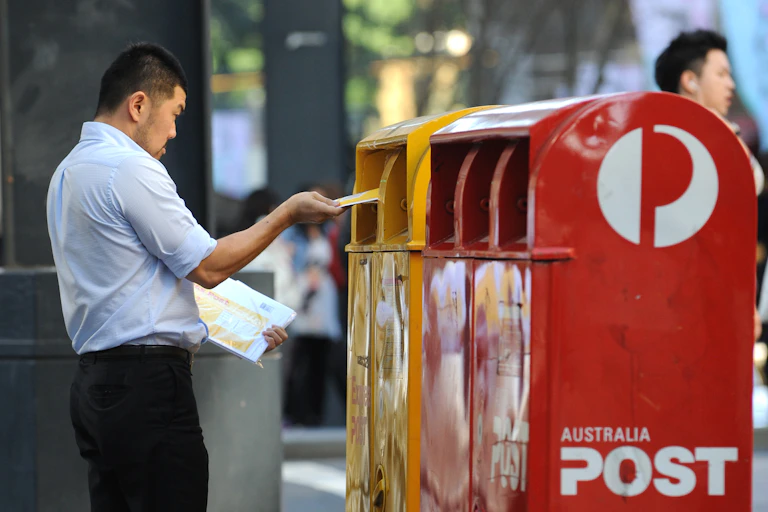 Man posting letters into Australia Post mailbox
