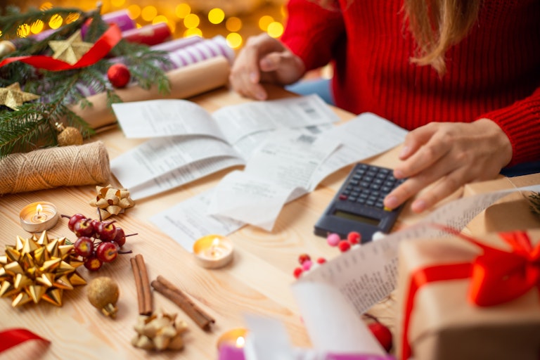Woman surrounded by Christmas decorations using calculator