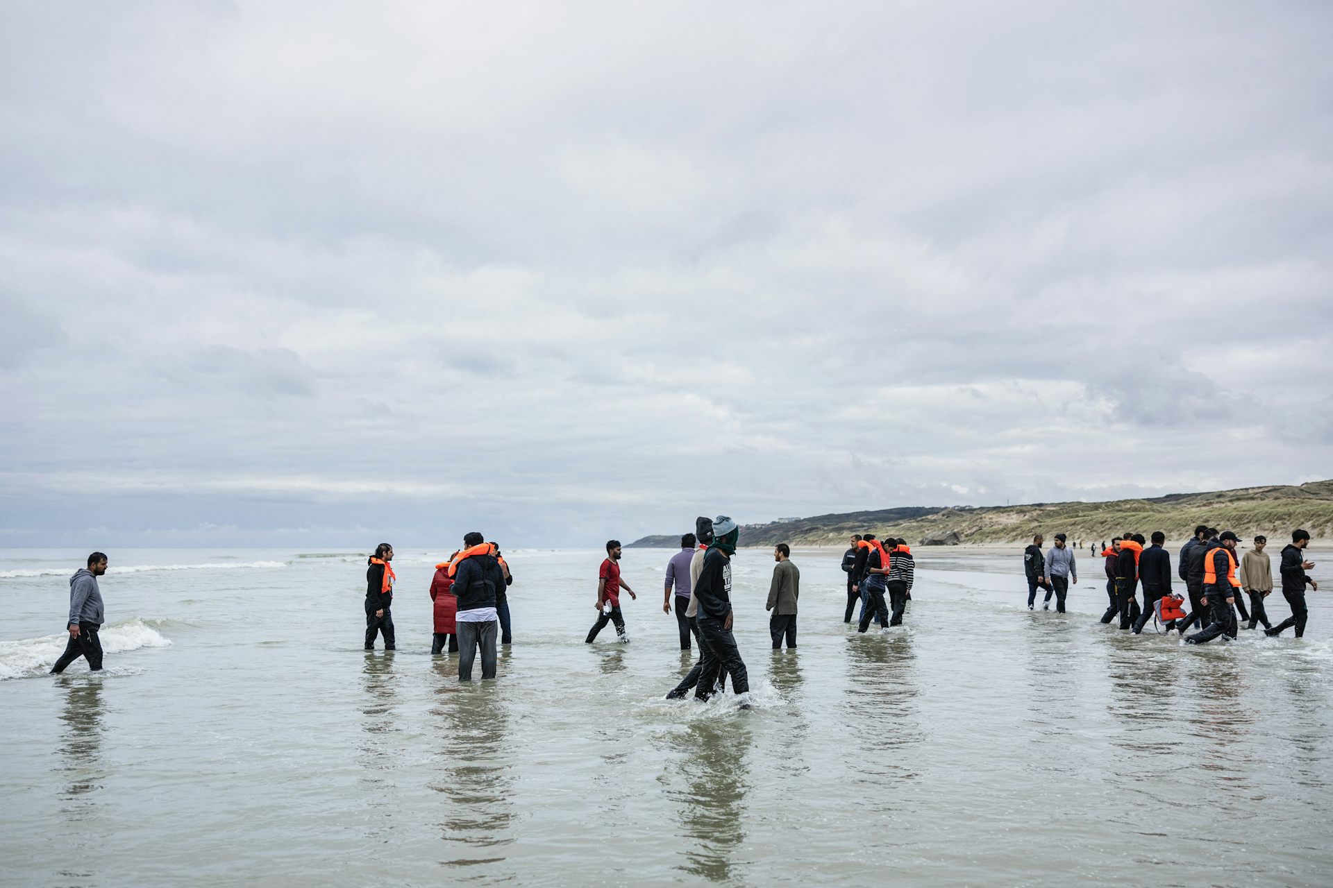 Des migrants regagnent la plage après le départ du canot pneumatique d'un passeur qui tentait de traverser la Manche, sur la plage de l'Ecault à Saint-Etienne-au-Mont, dans le nord de la France, le 30 octobre 2024.