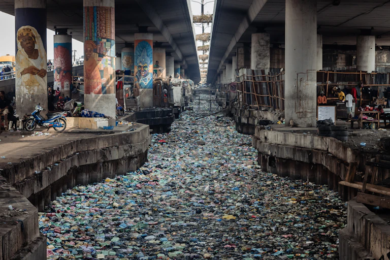 Concrete pillars holding up a bridge, and a channel between the pillars clogged with garbage