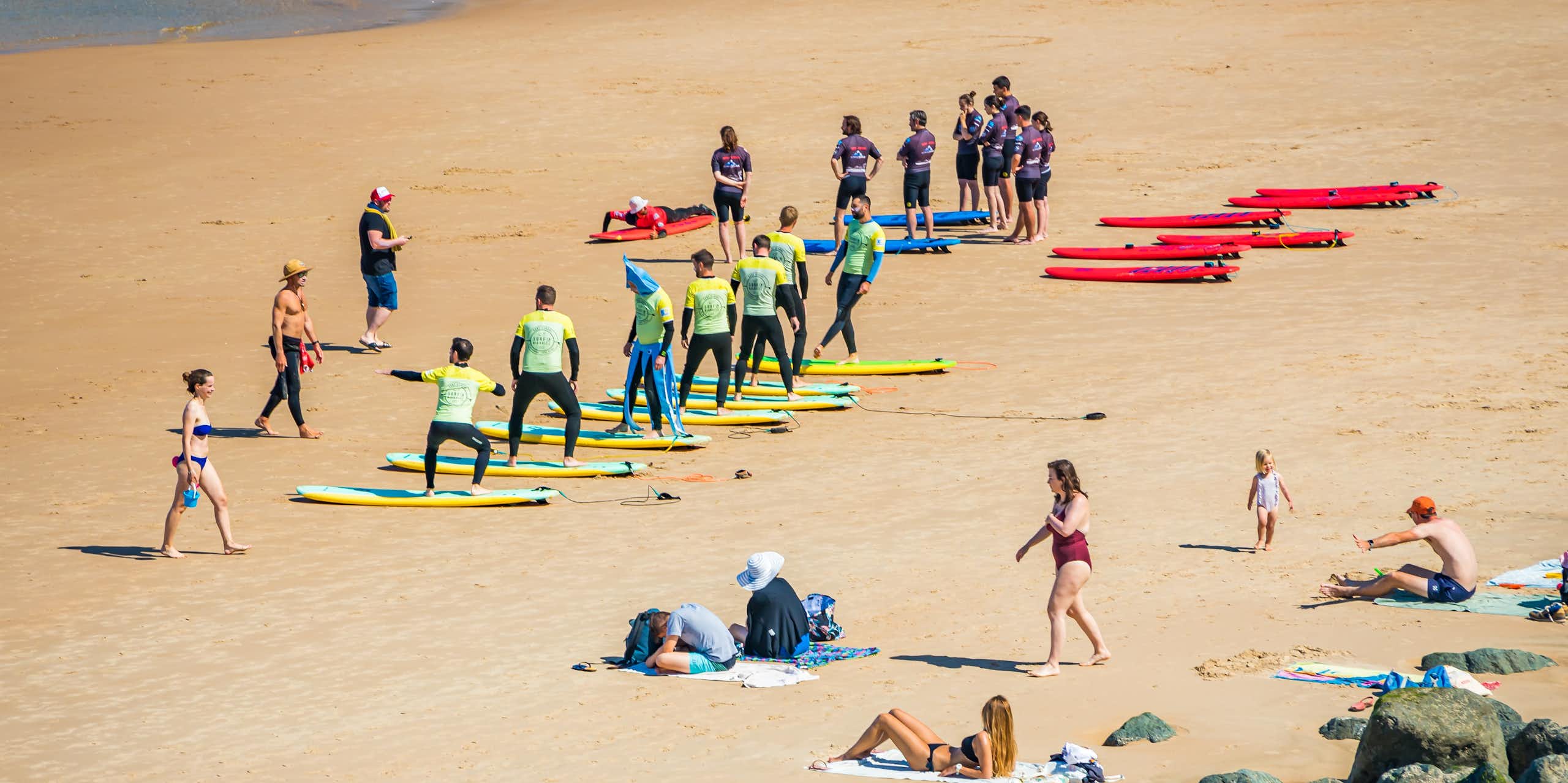 Surfing beginners learn surfing moves on a beach.