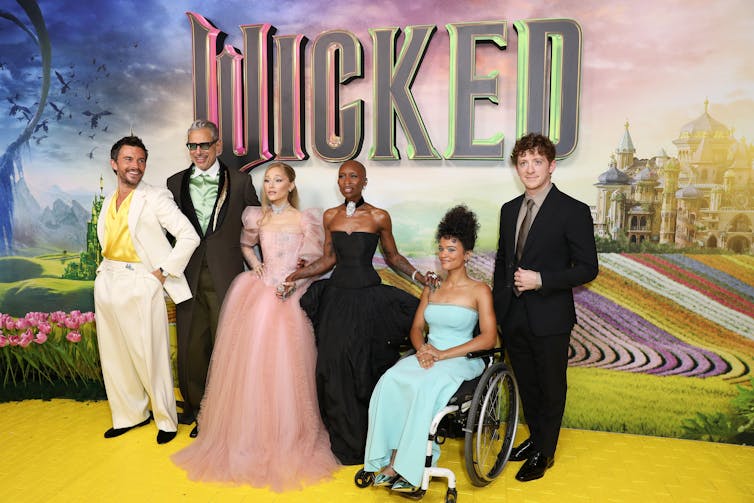 Marissa Bode on the red carpet in a blue dress, with other cast members.