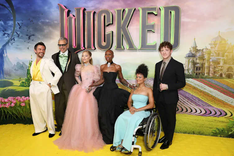 Marissa Bode on the red carpet in a blue dress, with other cast members.