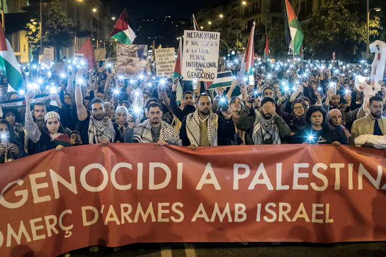 Spanish protesters hold and banner and call on their government to end its arms trade with Israel.
