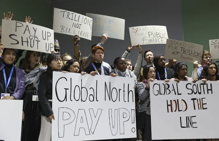 People holding signs saying 'Global North pay up'
