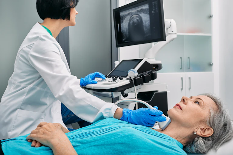 Une médecin fait passer une échographie de la thyroïde à une femme.