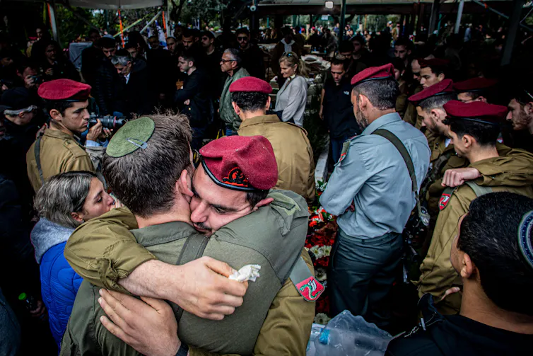 Israeli soldiers comfort each other at a funeral of their colleague.