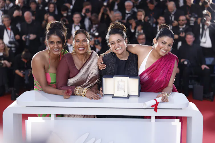 Four women smile and pose for a photo on a red carpet