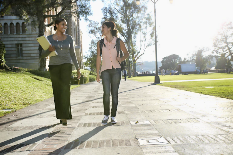 Two women walk on a college campus.