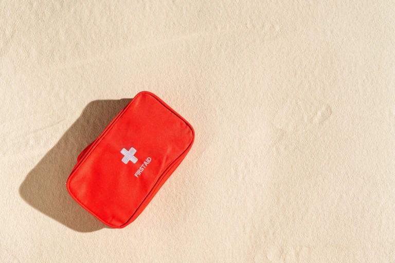 red first aid kit sits on sand