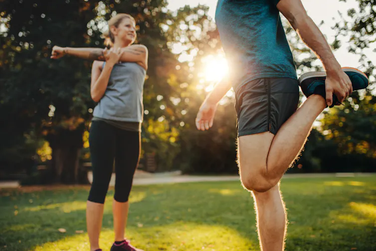 A man and women stretching in a park.