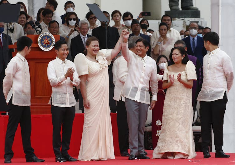 Philippines president Ferdinand 'Bongbong' Marcus, and his vice-president, Sara Duterte, clasp hands in a victory salte after breng sworn in to office in June 2022.