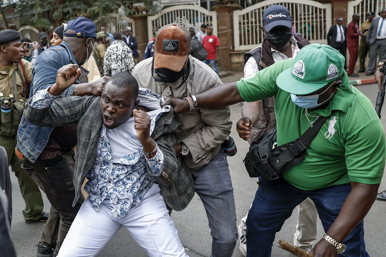 A man is grabbed by his clothes by three men dressed in jeans, T-shirts and jackets