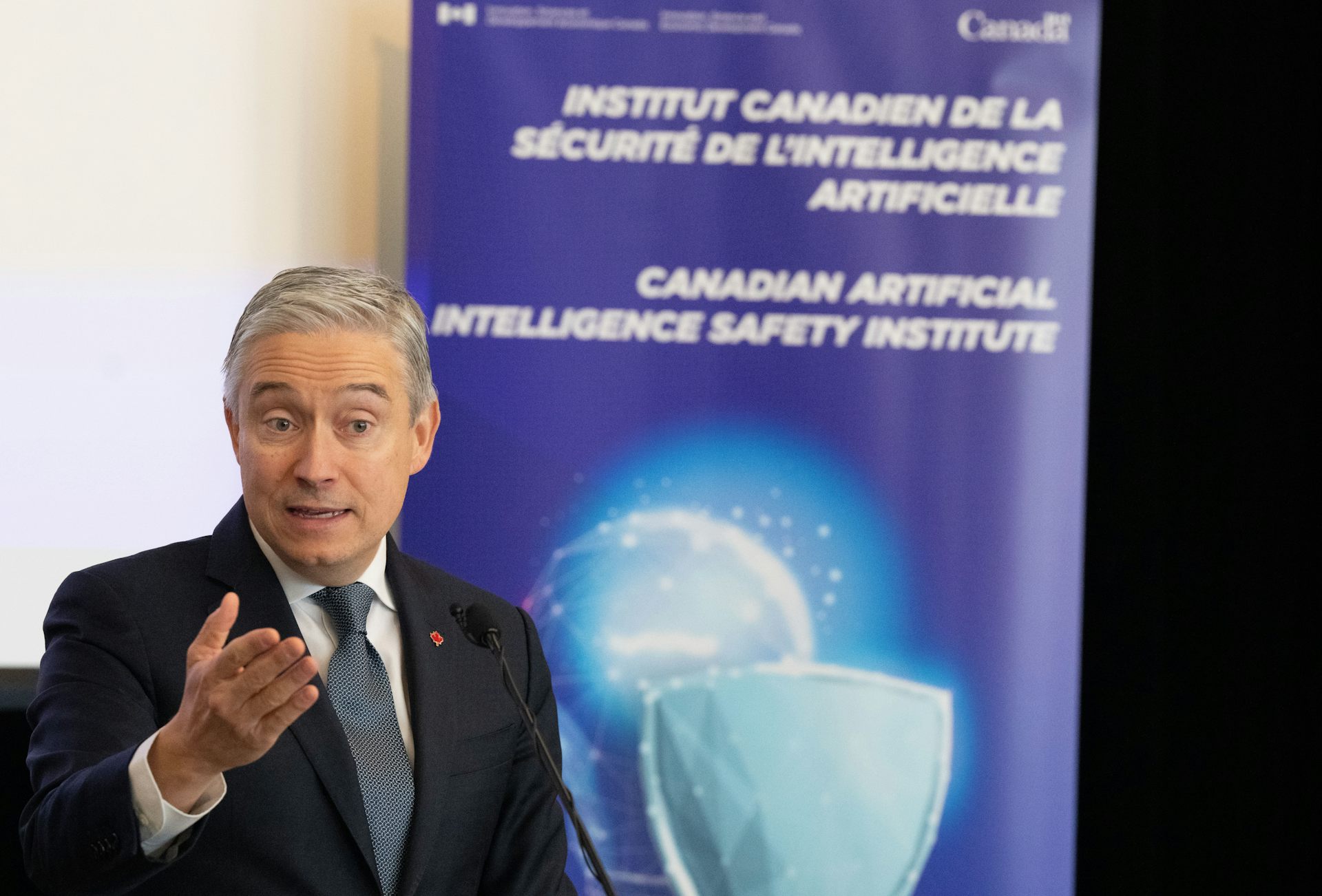 A man gestures with his hand while speaking to an audience off screen