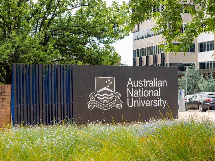 Australian National University sign on a wall in Canberra on a cloudy day.