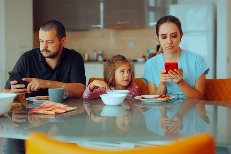 Parents look at their phones at the table