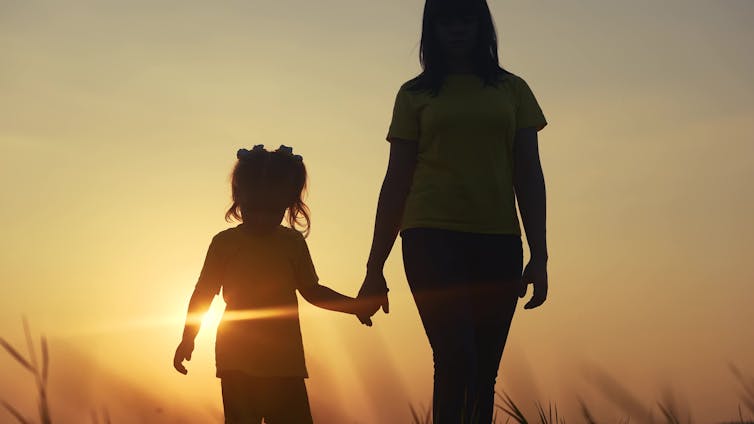 Mother walks with child at sunset