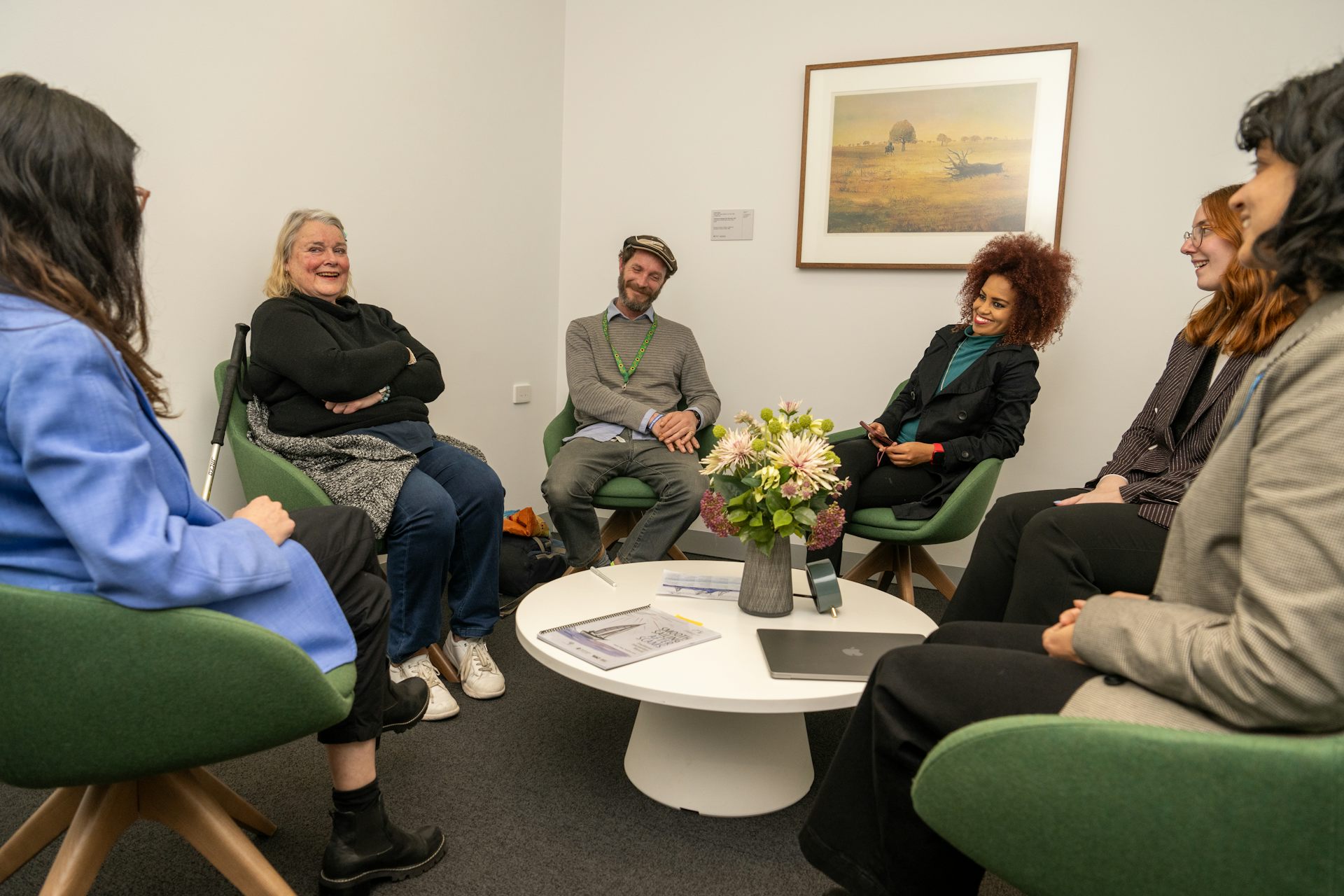 A group of people sitting in a circle on chairs and laughing.