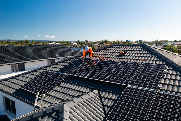man on roof installing solar panel