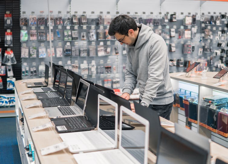 man browses laptops in a technology store