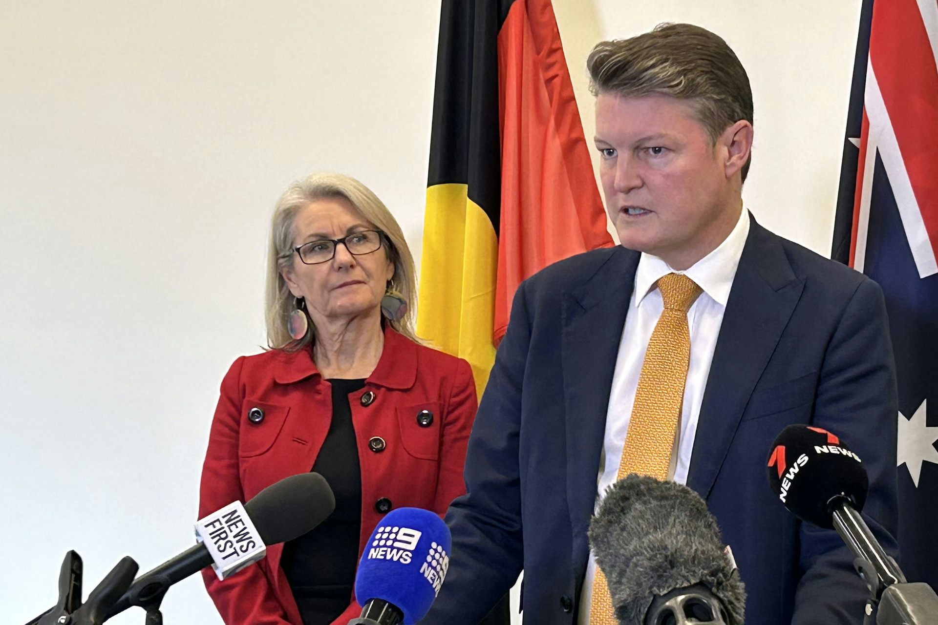 Victorian Education Minister Ben Carroll stands in front of microphones.