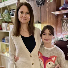 A young woman standing in a gift shop with her arm around her daughter.