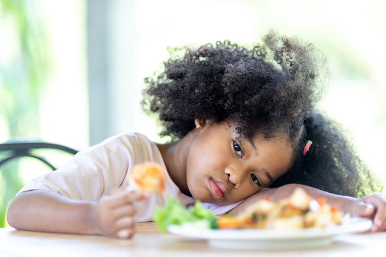 Girl looks uninterested at a plate of food