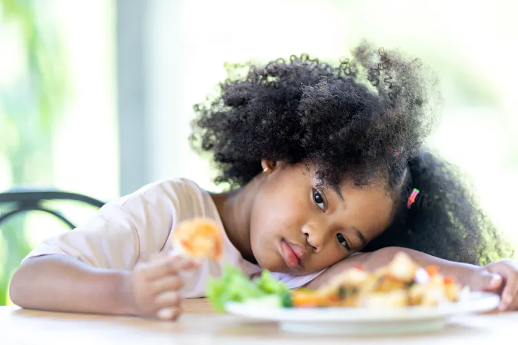 Girl looks uninterested at a plate of food