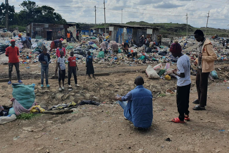 10 people standing around plastic waste site in Africa