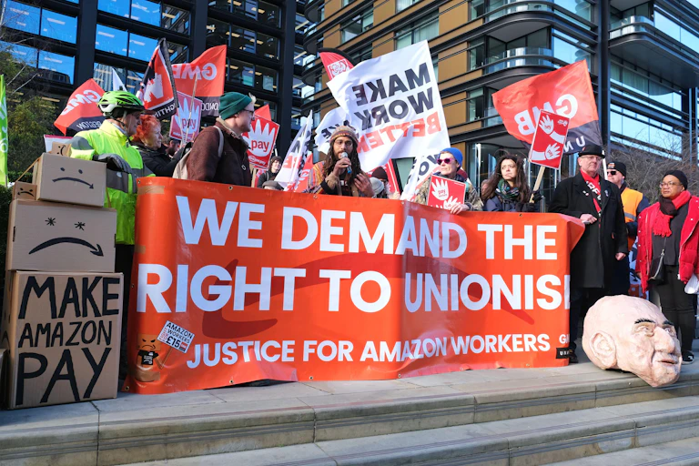 Amazon workers hold up a banner saying 'We demand the right to unionise'