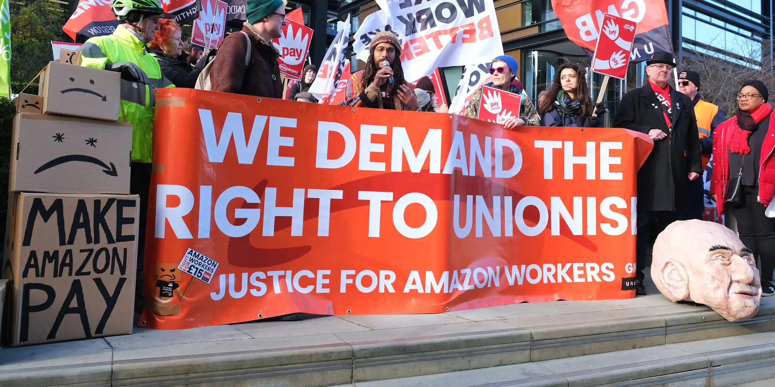 Amazon workers hold up a banner saying 'We demand the right to unionise'