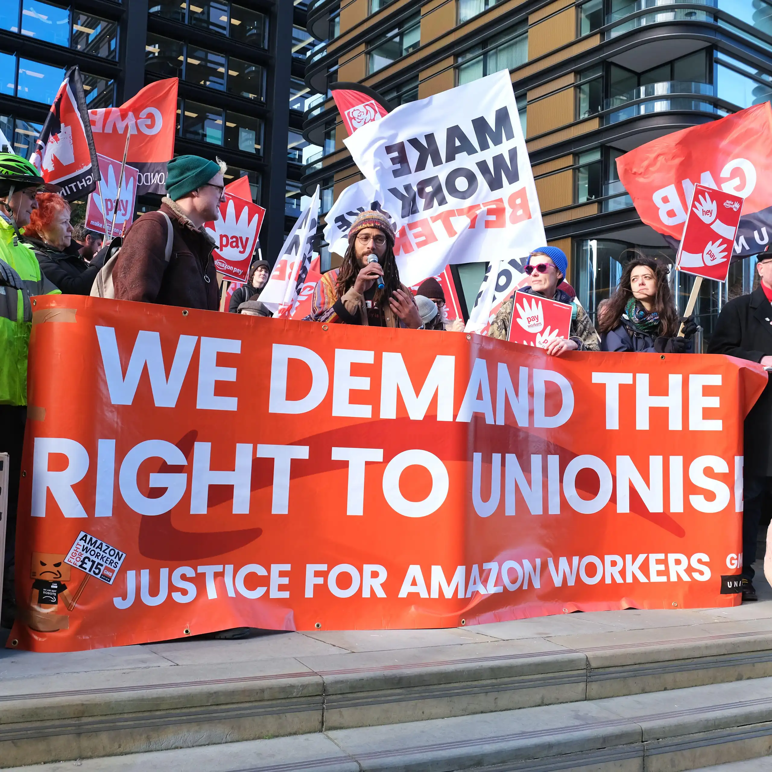 Amazon workers hold up a banner saying 'We demand the right to unionise'
