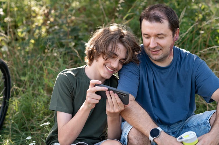 Father and son look at phone