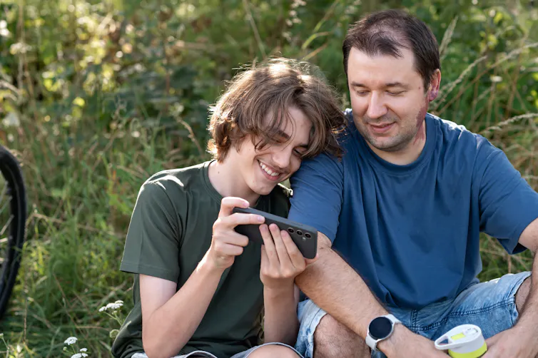 Father and son look at phone
