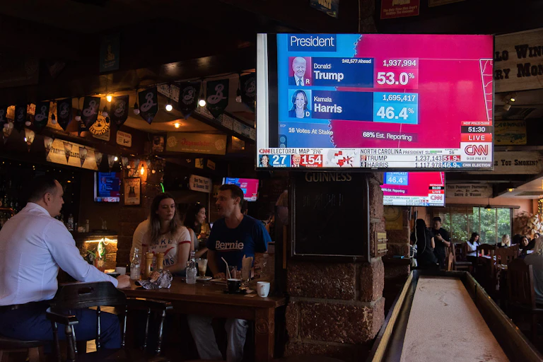 Three people in a bar with the television tuned to the US election result.
