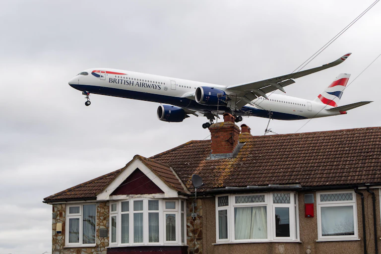 A British Airways aircraft flying over a house.