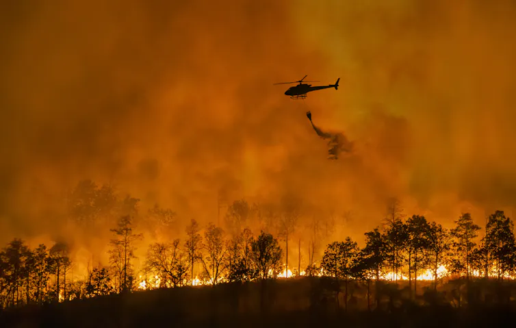 silhouette wildfire, helicopter flying over red sky